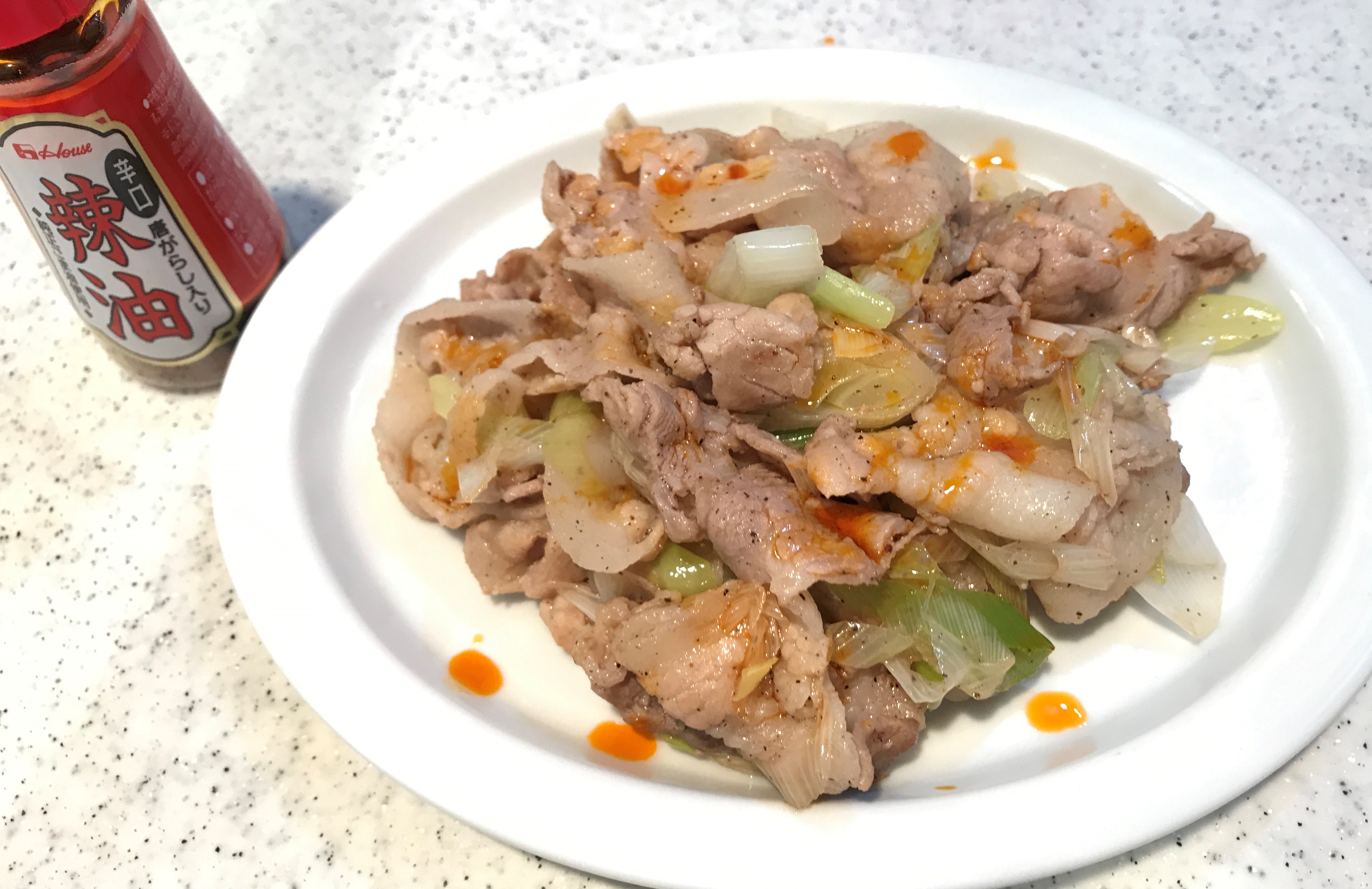 豚バラと長ネギにラー油をかける